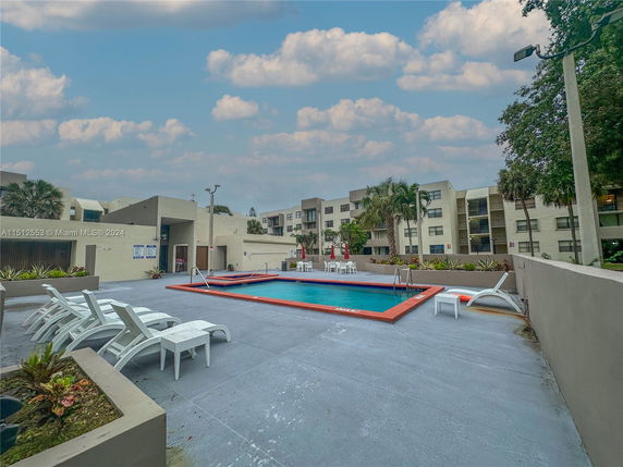 Outdoor swimming pool with lounge chairs and building in the background.