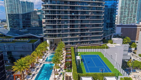 View of a modern residential complex with a tennis court and swimming pool.