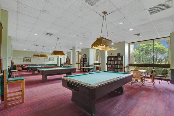 Interior of a recreation room with pool tables and bookshelves.