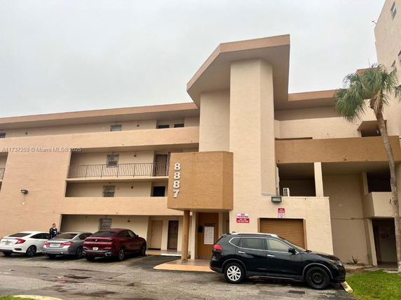 Front view of a multi-story building with parking area.
