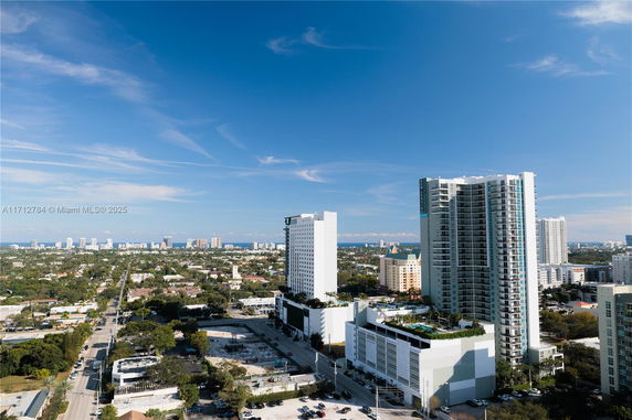 Panoramic view of city skyline with high-rise buildings and ocean in the background.