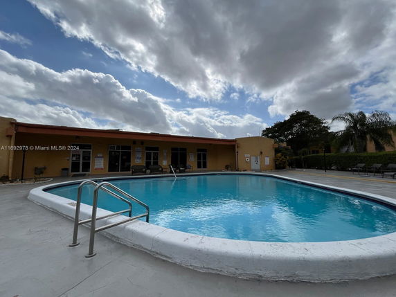 Outdoor swimming pool with a building in the background.