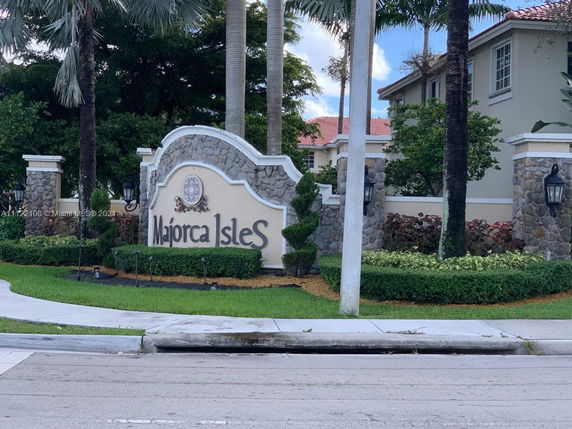 Front view of a community entrance with stone wall and sign.