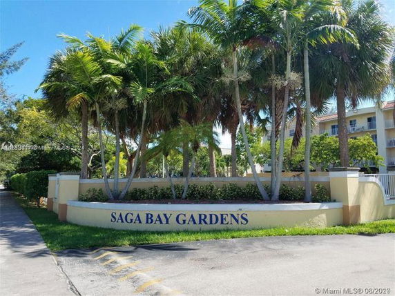 Front view of a multi-story residential building with palm trees in front.