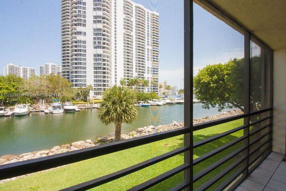 View from building balcony showing tall apartment building and water body.