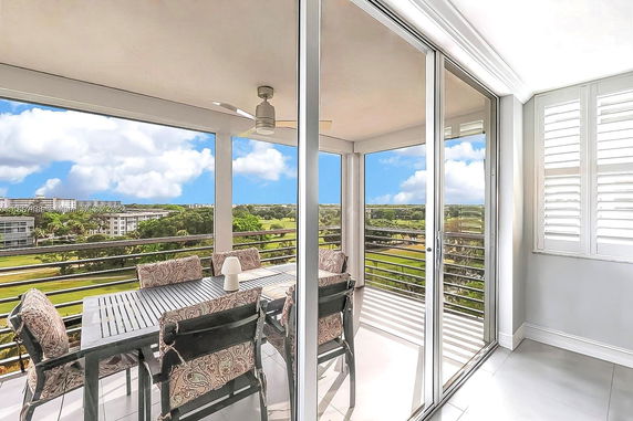 View from a balcony with a dining table, overlooking greenery and buildings in the distance.