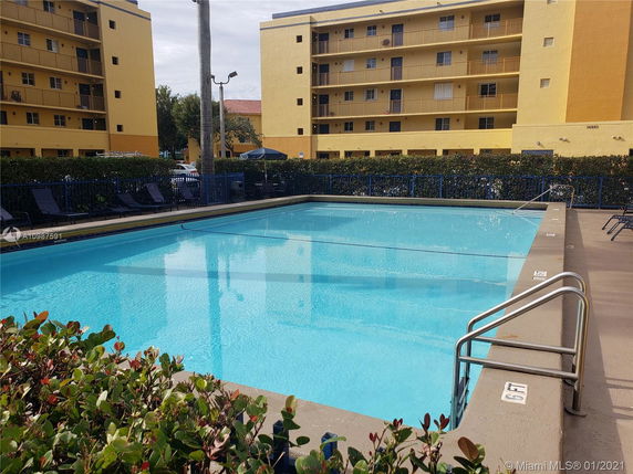 Outdoor view of a swimming pool in front of a multi-story residential building.