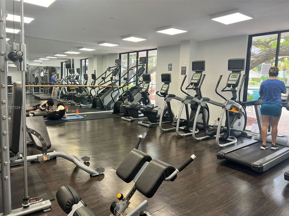 Indoor gym area with exercise machines and mirrors.