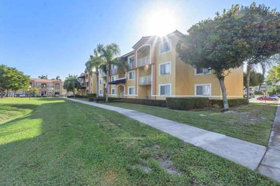 Front view of a multi-story residential building with balconies and a pathway.