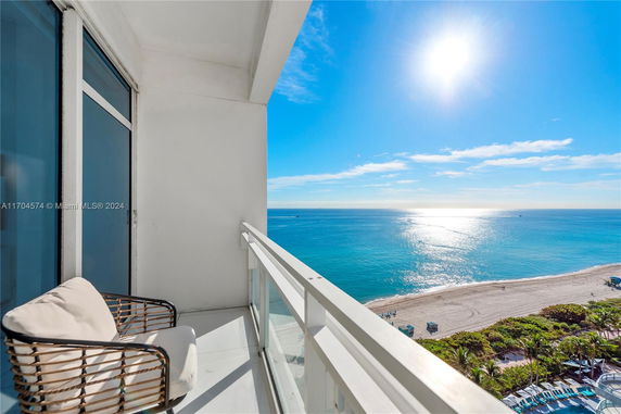Balcony with a chair overlooking the ocean and beach.