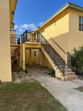 Front view of a two-story building with exterior stairs and yellow walls.