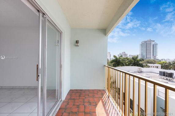 View from a balcony looking towards nearby buildings and palm trees.