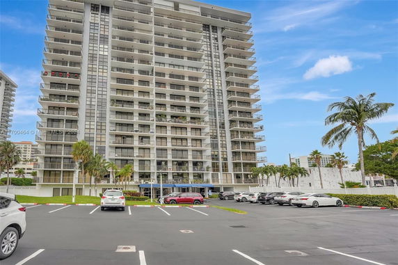Front view of a high-rise apartment building with balconies and parking area.