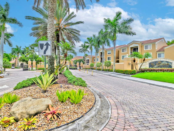 Front view of a multi-story residential building with palm trees and landscaping.