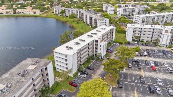 Aerial view of apartment buildings near a water body with parking areas.