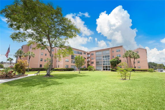 Front view of a multi-story apartment building with a large lawn.