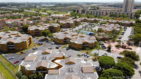 Aerial view of a residential complex with multiple yellow buildings and parking areas.