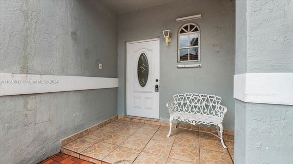 Front view of a house entrance with a white door and decorative bench.