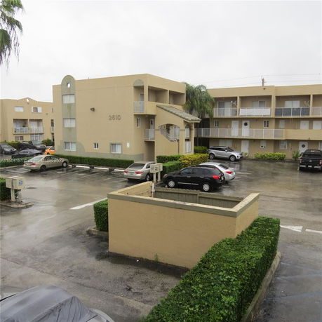 Front view of an apartment building with multiple stories and parking area.