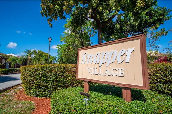 Sign for Snapper Village with greenery and trees in the background.