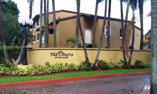 Front view of a beige two-story building with a name sign and palm trees.
