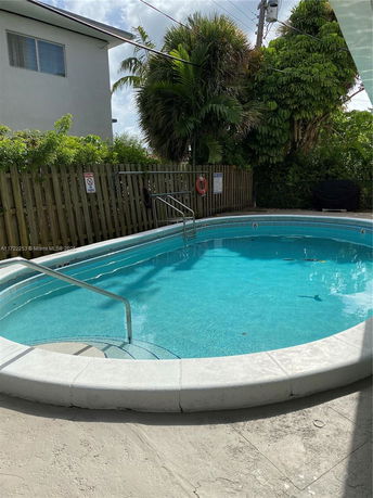 A round outdoor swimming pool with a railing and surrounding fence.