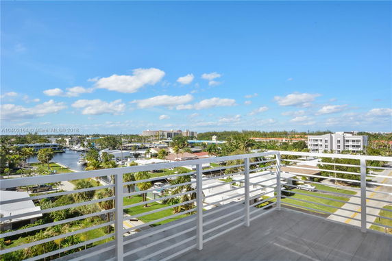 Panoramic view from a balcony overlooking a residential area with waterway and distant buildings.
