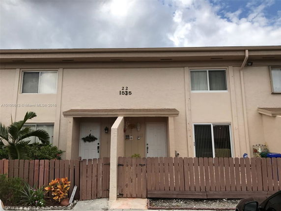 Front view of a two-story townhouse with a fenced entrance.