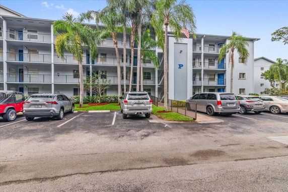 Parking area in front of a multi-story apartment building with balconies.
