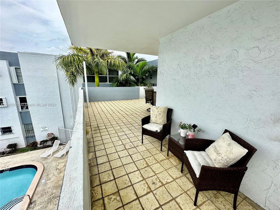 A rooftop area with seating overlooking a swimming pool.