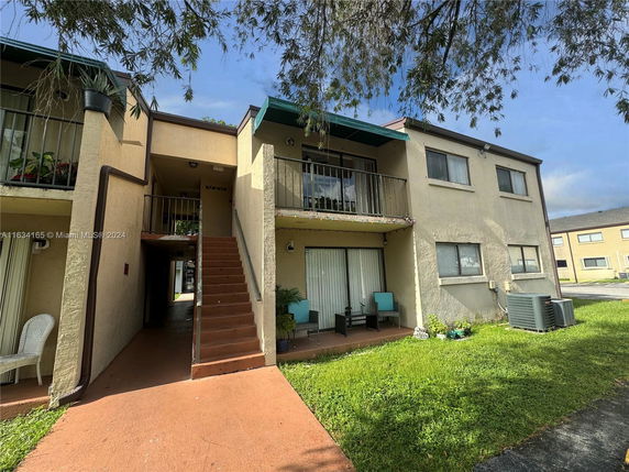Front view of a multi-story residential building with balconies and external staircase.