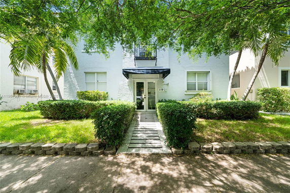 Front view of a two-story house with light exterior and a canopy over the entrance.