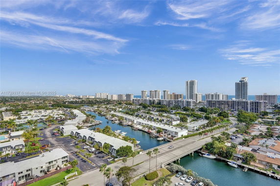 Wide angle view of a coastal city with waterways, residential buildings, and high-rise structures.