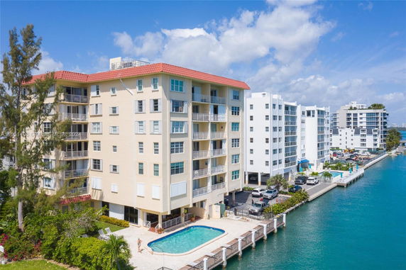 Exterior view of a multi-story apartment building with a swimming pool beside a waterway.