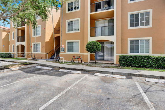 Front view of a multi-story residential building with designated parking spaces.