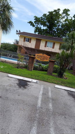 Front view of a two-story apartment building with an external staircase.