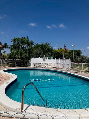 Outdoor swimming pool area with surrounding chairs and fence.