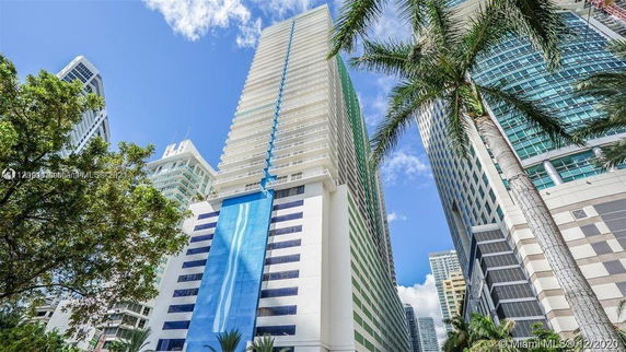 Front view of a tall modern high-rise building with a distinctive blue vertical stripe facade.