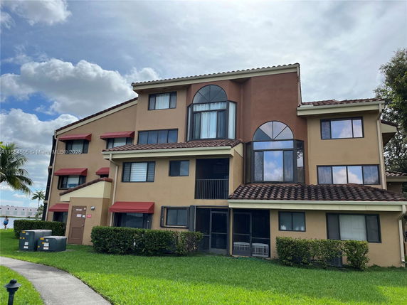 Front view of a multi-story residential building with large windows and red awnings.