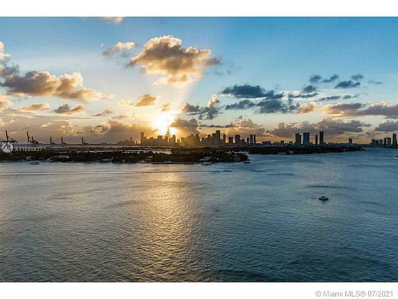 Panoramic view of a city skyline at sunset with water in the foreground.