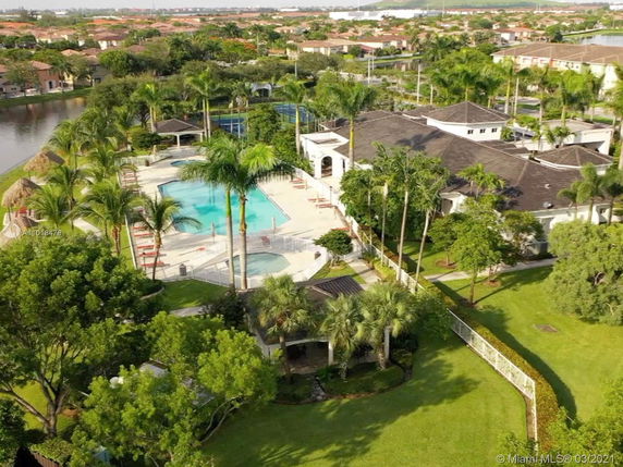 Aerial view of a clubhouse area with a swimming pool surrounded by palm trees and greenery.