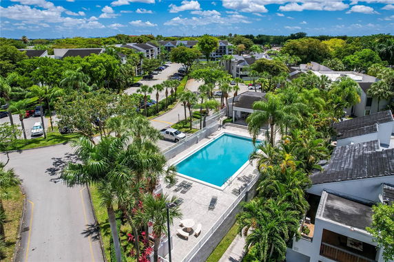 Aerial view of a residential complex with a central swimming pool surrounded by palm trees.