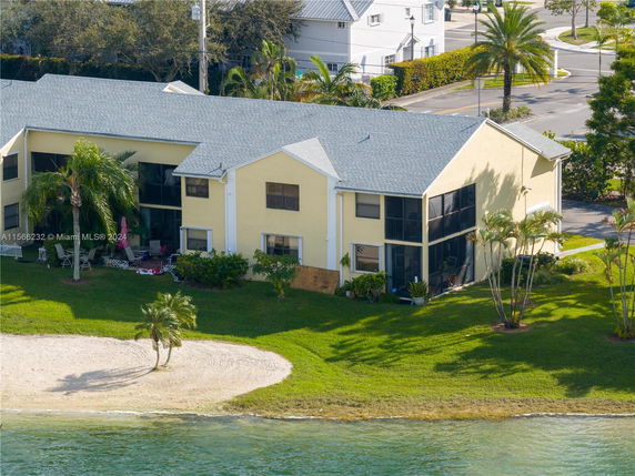 Two-story house with a lakefront view and surrounding grassy area.
