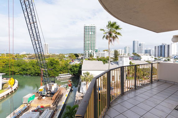 Balcony view of a river, construction equipment, and tall buildings in the distance.
