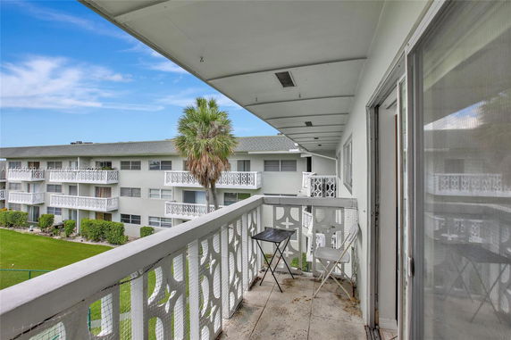 Balcony view of an apartment complex with decorative railings and a green lawn.