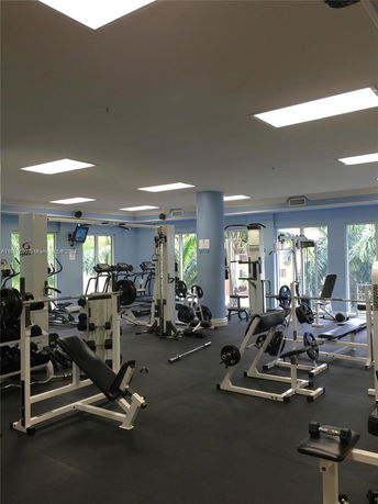 Indoor gym area with various exercise equipment and machines.