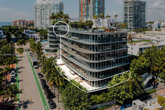 Front view of a multi-story building with glass balconies and a rooftop garden.