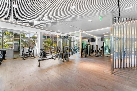 Interior view of a modern gym with exercise equipment and large windows.