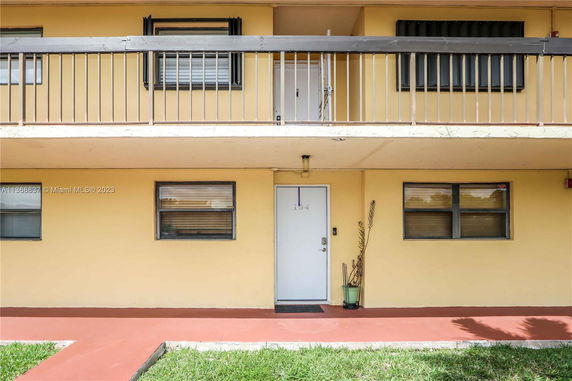 Front view of a two-story building with balconies and a white door labeled 104.
