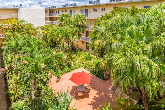 View of a multi-story building with balconies and lush greenery surrounding the courtyard.